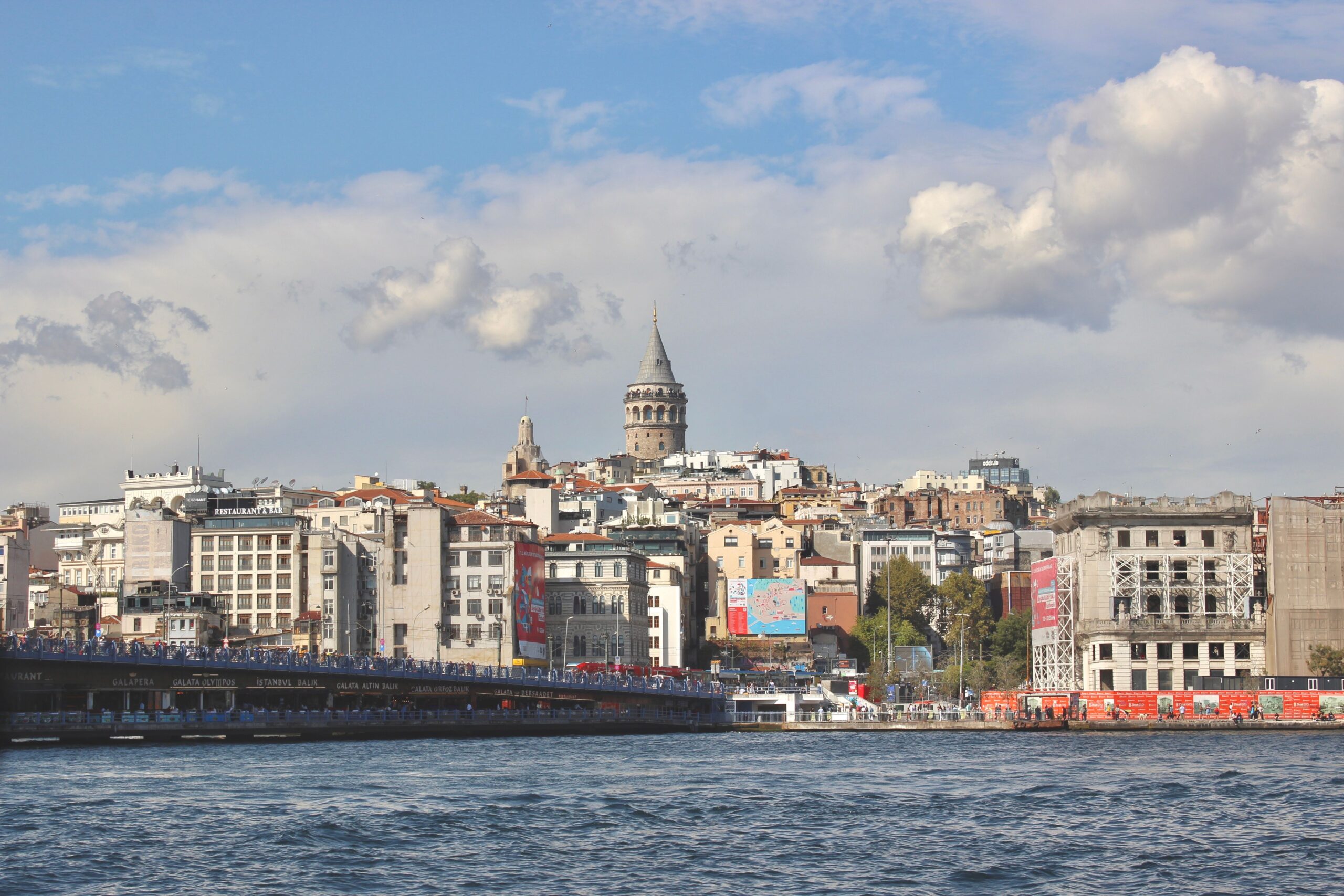 Beautiful view of Galata Tower and Istanbul's cityscape by the Bosphorus under a clear sky.